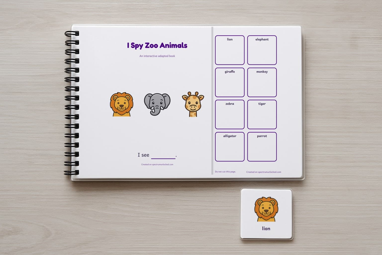 The I Spy Zoo Animals adapted book closed on a table, its cover facing up, one picture card beside it