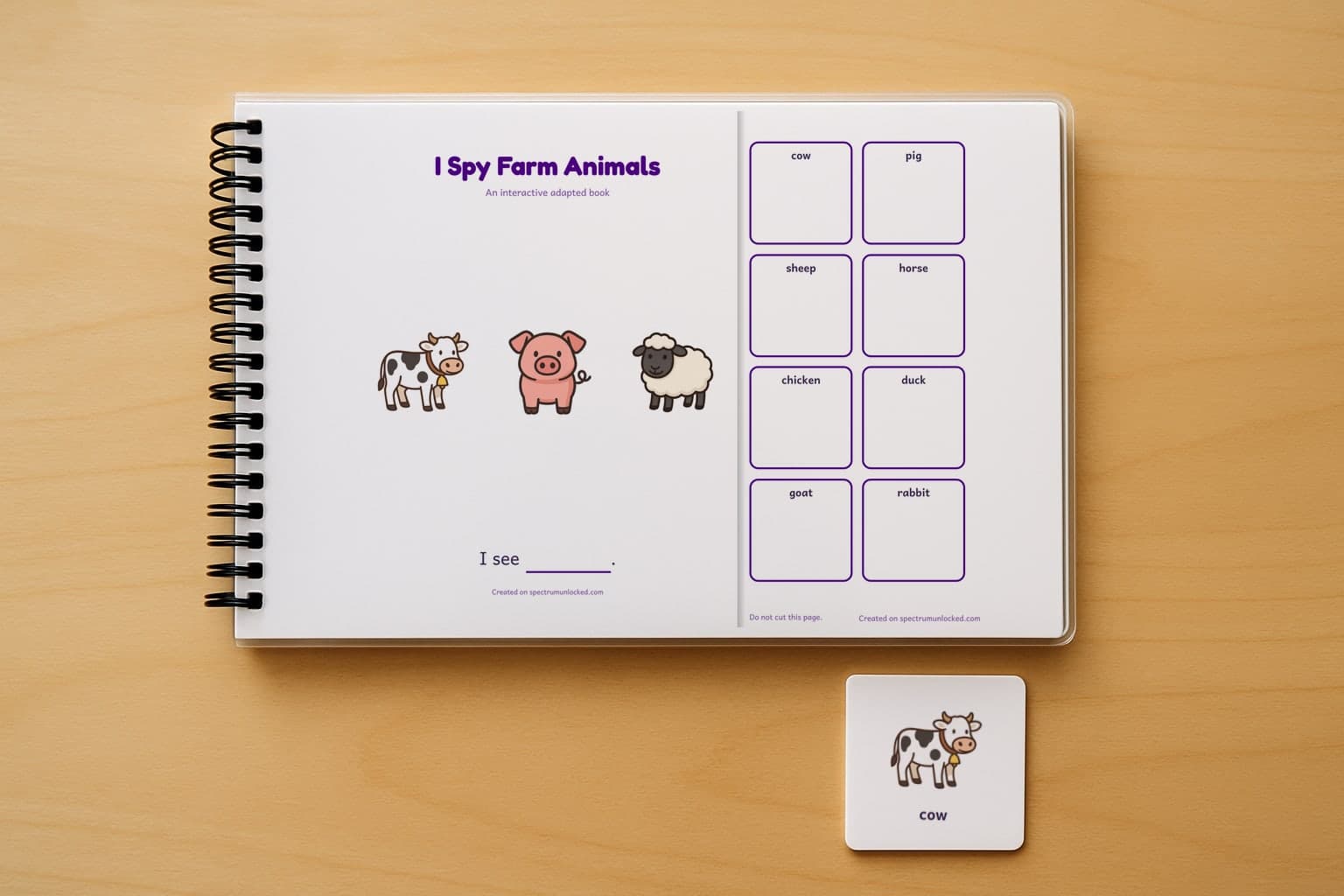 The I Spy Farm Animals adapted book closed on a table, its cover facing up, one picture card beside it