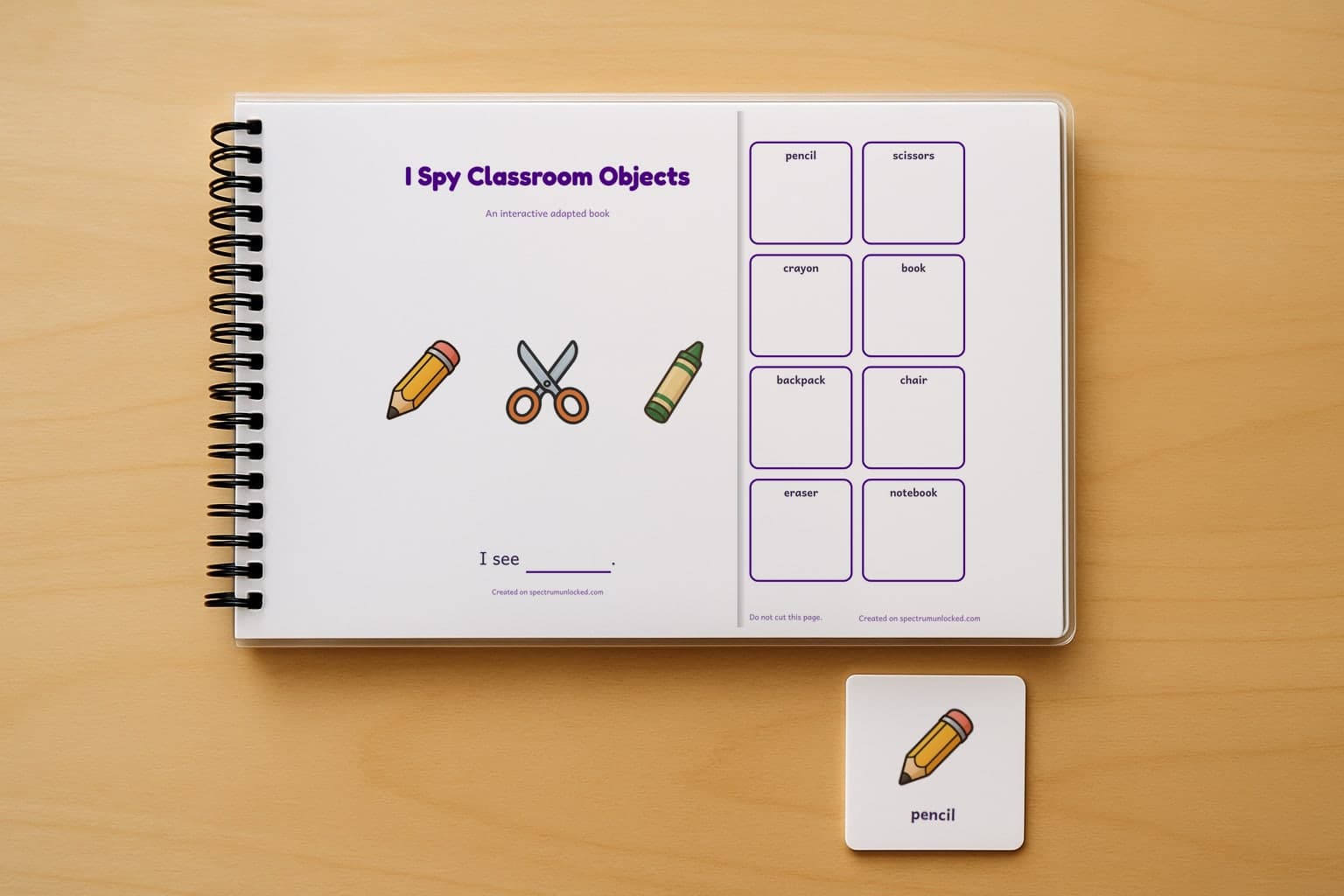 The I Spy Classroom Objects adapted book closed on a table, its cover facing up, one picture card beside it