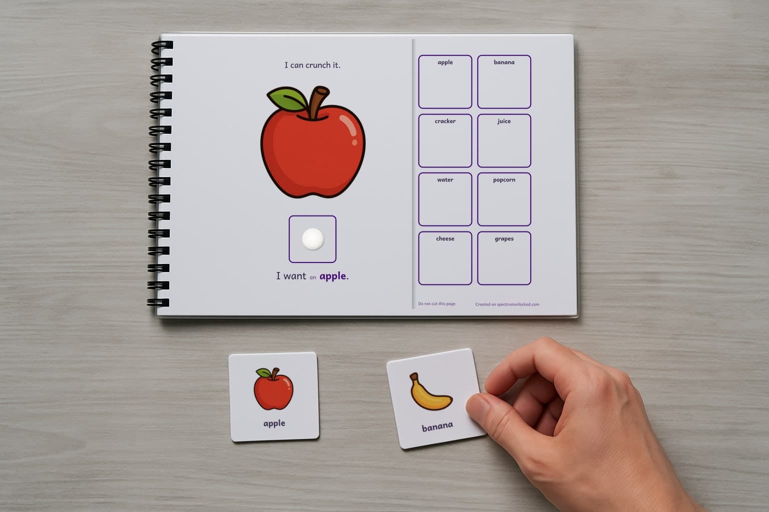 A page of the Snack Choices adapted book, laminated and spiral bound, with a child's hand holding a picture card beside it