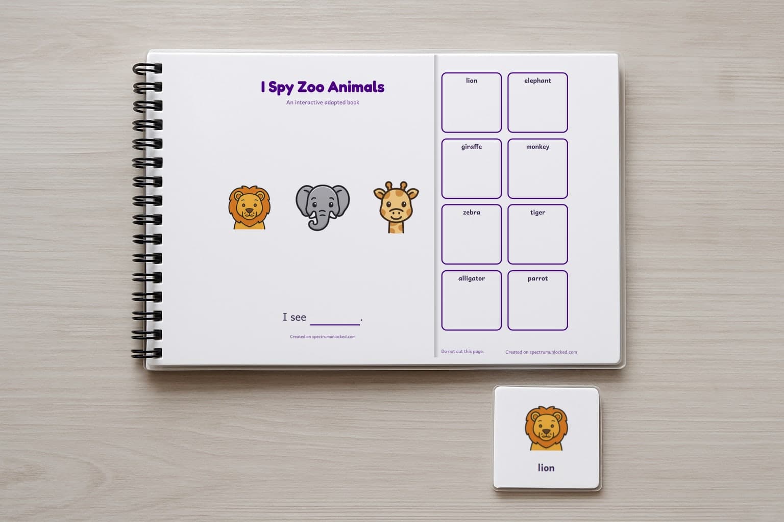The I Spy Zoo Animals adapted book closed on a table, its cover facing up, one picture card beside it