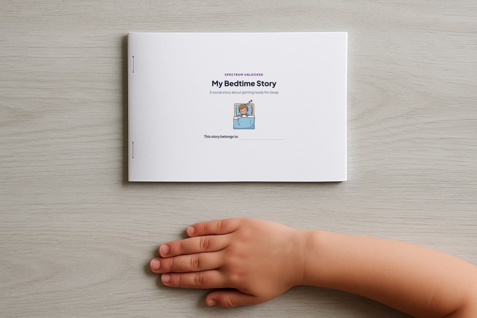 The Bedtime social story printed and stapled into a small booklet, closed on a table with a child's hand beside it